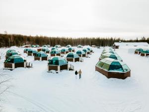 people standing in the snow next to a group of tents at Arctic SnowHotel & Glass Igloos in Sinettä
