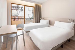 two beds in a hotel room with a window at Hotel Andalucía in Benidorm