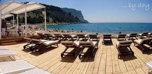 a group of chairs and tables on a wooden deck near the beach at Appartement le Mehari in Cassis