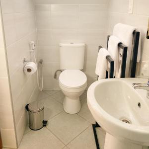 biała łazienka z toaletą i umywalką w obiekcie Heart of Africa Lodge w mieście Arusza