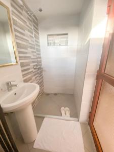 ein Bad mit einer Dusche, einem Waschbecken und einem WC in der Unterkunft Heart of Africa Lodge in Arusha