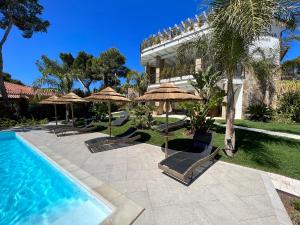 un complexe avec une piscine bordée de parasols dans l'établissement Villa Aquamarina Pintadera Rossa, à Porto Pino