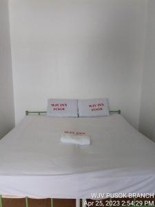 Una cama con dos almohadas blancas encima. en WJV INN PUSOK en Pajo