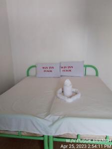 Una cama con dos almohadas y un animal de peluche. en WJV INN PUSOK en Pajo