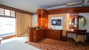 Habitación de hotel con cama, escritorio y TV. en Hotel Savoy Homann, en Bandung