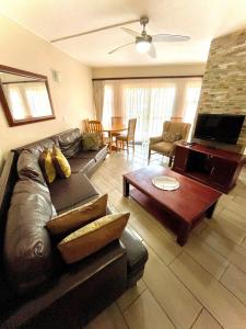 a living room with a leather couch and a coffee table at Perna Perna Lodge St Lucia in St Lucia