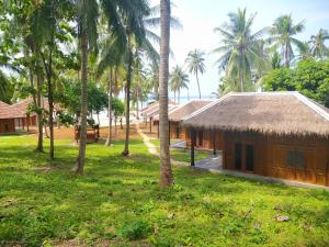 a house with a straw roof and palm trees at Eco Casa in Karimunjawa