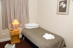 a hotel room with a bed and a lamp and a window at The Alpine Hotel in Cooma