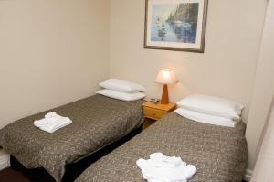 two beds in a hotel room with towels on them at The Alpine Hotel in Cooma