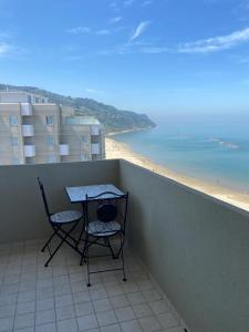 einen Tisch und zwei Stühle auf einem Balkon mit Strand in der Unterkunft Tramonto in Baia in Pesaro