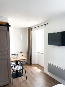Zimmer mit einem Tisch und einem TV an der Wand in der Unterkunft STUDIOS Neufs - COEUR de Barcelonnette - Parking privé in Barcelonnette