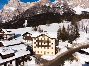 a building in the snow with a mountain at Appartamento NeveSole in San Vito di Cadore