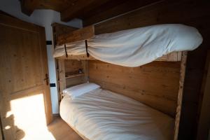 a bedroom with a bunk bed with white sheets at Appartamento NeveSole in San Vito di Cadore