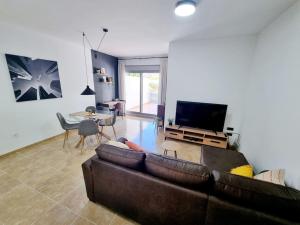a living room with a brown couch and a television at Cal Marc - Piso con piscina y terraza in Ulldecona