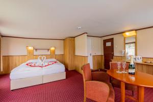 Fortuna Boat Hotel Budapest في بودابست: غرفة نوم مع سرير وطاولة مع زجاجة من النبيذ