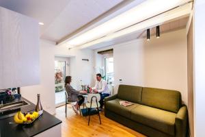 a living room with a couch and two people sitting at a table at San Tommaso Suites in Canelli