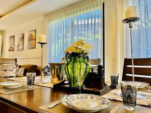 a table with a green vase with flowers in it at Country club townhouse in Bang Tao Beach