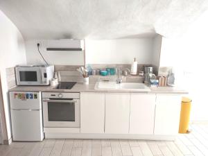 a white kitchen with a sink and a microwave at Les insolites de Champeix in Champeix