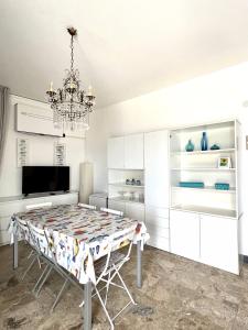 una sala da pranzo con tavolo e lampadario pendente di Appartamento Direttamente sul Mare a Finale Ligure