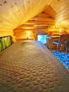 a large bed in a room with wooden ceilings at Mökki järven rannalla mäntymetsässä in Forssa