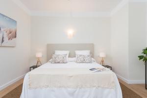a white bedroom with a white bed with two lamps at Boutique Hotel Oriola in Cala de Sant Vicenc