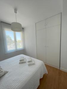 biała sypialnia z łóżkiem z 2 ręcznikami w obiekcie Apartamento Colina B 19. w Kordobie