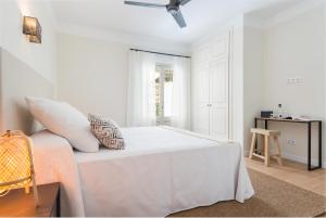 a white bedroom with a bed and a window at Boutique Hotel Oriola in Cala de Sant Vicent