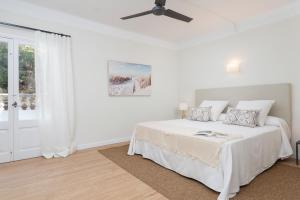 a white bedroom with a bed and a ceiling fan at Boutique Hotel Oriola in Cala de Sant Vicenc