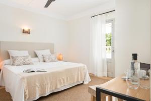 a white bedroom with a bed and a table at Boutique Hotel Oriola in Cala de Sant Vicenc