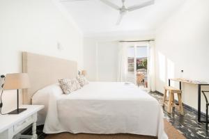 a white bedroom with a bed and a table at Boutique Hotel Oriola in Cala de Sant Vicenc