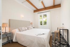 a white bedroom with a bed and a window at Boutique Hotel Oriola in Cala de Sant Vicenc