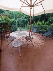 a patio with a table and chairs and an umbrella at Casina Laura in Capannori
