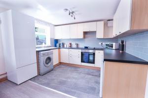 a kitchen with white cabinets and a washing machine at Beautiful 2 Bedroom,freeParking L Buzzard in Leighton Buzzard