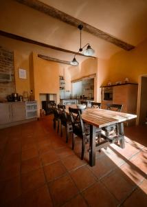 une grande cuisine avec une table et des chaises en bois dans l'établissement Les Lauriers Roses - Maison d'Hôtes, à Barjac