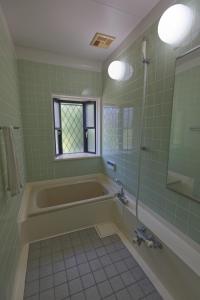 a green bathroom with a tub and a window at ocean resort mint オーシャンビューを満喫!かわいい三角屋根の三階建て貸切別荘 in Shioura