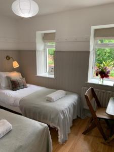 a bedroom with two beds and a desk and two windows at The Old Dairy in Bushmills