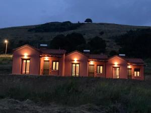 una casa con luces encendidas en un campo por la noche en Red Village Limnos en Moúdhros