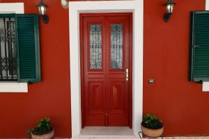 czerwone drzwi na boku domu w obiekcie Zeitouni Lodge w mieście Katávolos