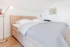 una camera da letto con un letto con cuscini bianchi e una lampada di Haus Eva Mar am Meer Appartement 4 a Timmendorfer Strand