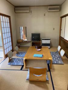 a room with a table and chairs and a tv at Ryokan Fujitomita in Oshino