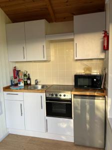 a kitchen with white cabinets and a black microwave at Pearl Shepherds Hut in Penally