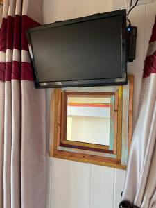 a mirror on a wall with a television on it at Pearl Shepherds Hut in Penally