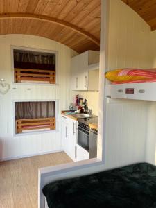 uma pequena cozinha com armários brancos e um fogão em Pearl Shepherds Hut em Penally