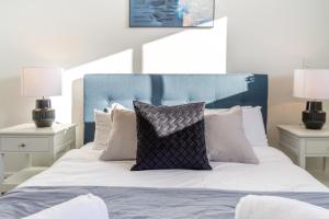 a bed with a blue headboard and white pillows at Stroll through the park 2 bed 2 bath w/carpark in Christchurch