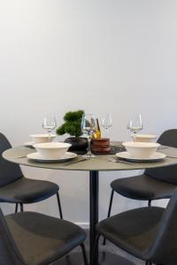 a table with chairs and plates and wine glasses at Stroll through the park 2 bed 2 bath w/carpark in Christchurch
