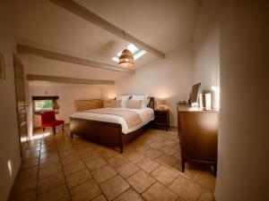 1 dormitorio con 1 cama y 1 silla roja en Les Lauriers Roses - Maison d'Hôtes, en Barjac