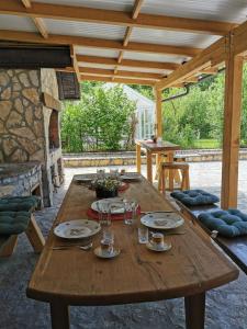 a wooden table with plates and glasses on it at Greenwood Cottage house for rent near Zagreb in Pisarovina