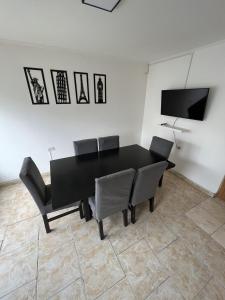 mesa de comedor negra con sillas y TV de pantalla plana en Alojamiento temporal La Josefina en Tandil