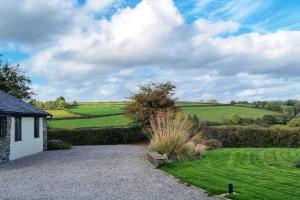 un jardin avec une allée en gravier et des champs verdoyants dans l'établissement Little Garden Cottage, Tamar Valley, Cornwall, à Stoke Climsland