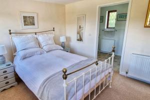 um quarto com uma cama grande com lençóis brancos e almofadas em Little Garden Cottage, Tamar Valley, Cornwall em Stoke Climsland